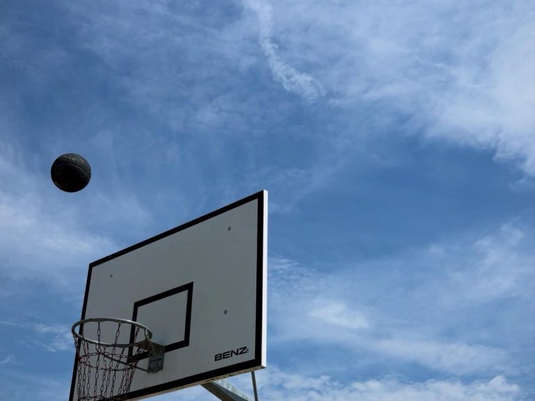 Ein Basketball fliegt auf den Korb des Außenplatzes zu