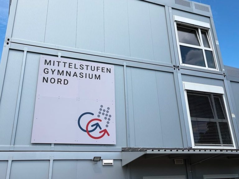 Das Schulgebäude mit dem Namensschild an der Fassade